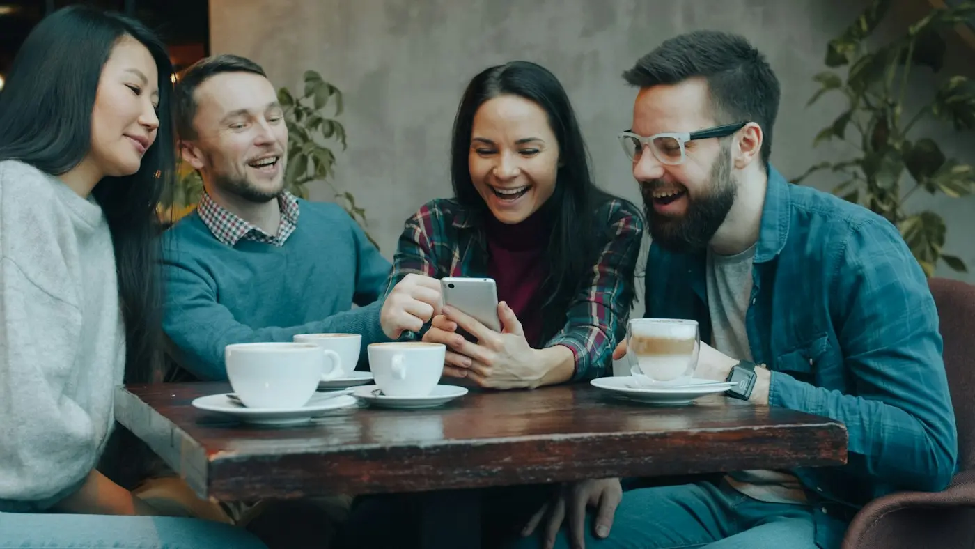 Friends laughing at something on a phone in a cafe